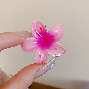Vue macro détaillée d'une mini pince à cheveux en forme de fleur rose dégradé brillant