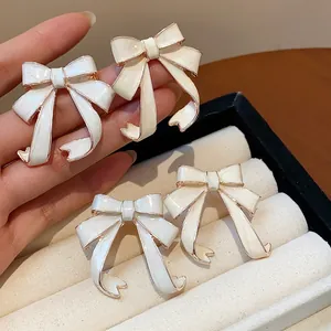 Detailed close-up showing elegant cream enamel bow stud earrings on a jewelry tray