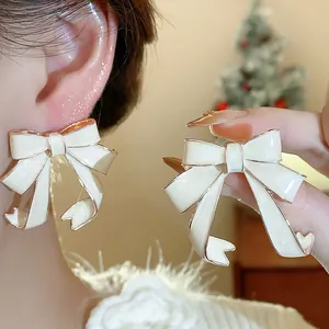 Detailed view of exquisite white oil-dripped bow-knot stud earrings with gold plating