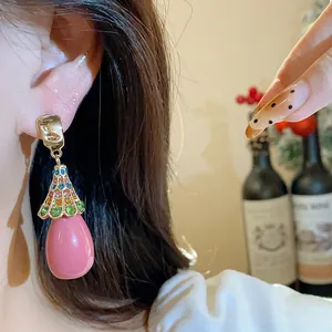 Close-up of vintage pink resin waterdrop earrings with colorful crystal accents on ear