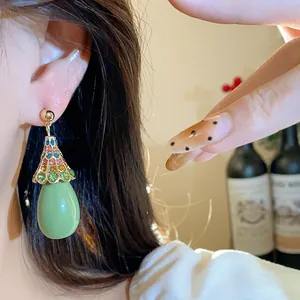 Close-up detail of vintage green resin drop earrings with colorful crystals on a model's ear