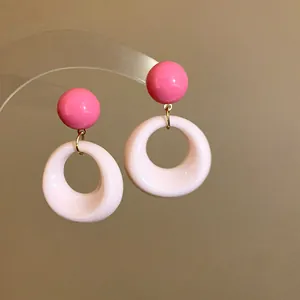 Vista dettagliata di eleganti orecchini pendenti tondi in acrilico rosa e bianco con ago argento