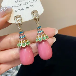 Close-up of vintage-style drop earrings with pink resin waterdrop and colorful rhinestones