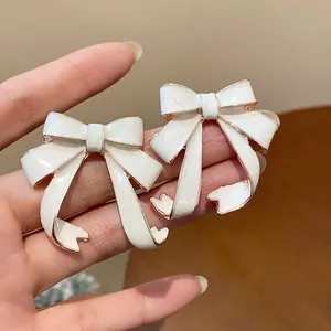 Close-up of elegant white enamel bow-knot stud earrings with rose gold metal trim