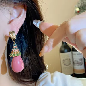 Close-up of a vintage pink teardrop earring with multi-color rhinestones on ear.