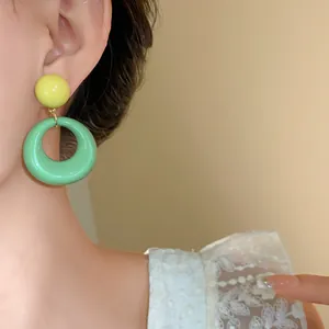 Primo piano di orecchini a cerchio in acrilico verde menta indossati da una modella