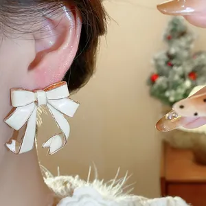 Close-up view of an elegant cream enamel bow stud earring worn on an ear, sweet style