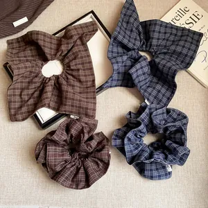 Detail of plaid fabric hair scrunchies in brown and navy blue on a textured surface