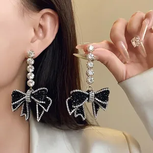 Boucles d'oreilles pendantes nœud noir exagéré avec strass brillants pour mode élégante.
