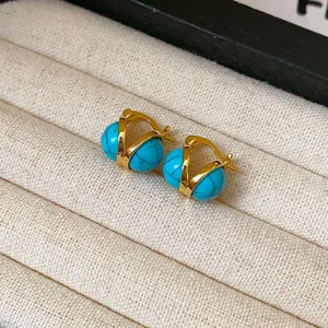 Primer plano detallado de pendientes de aro dorados con cuentas de resina azul dobles