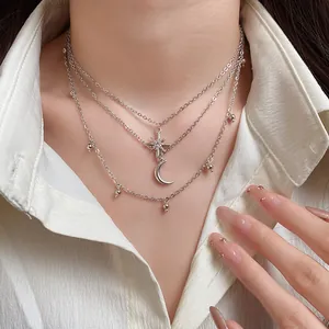 Macro view of a three-layered silver necklace with rhinestone star and moon pendants.