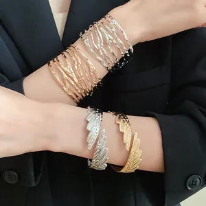 Detail view of metallic twisted and feather-shaped open cuffs in gold and silver finish