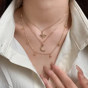 Close-up detail of a gold-tone layered necklace showing the star and moon charms