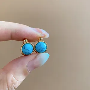 Primer plano de pendientes de aro redondos de resina turquesa y oro de estilo étnico retro