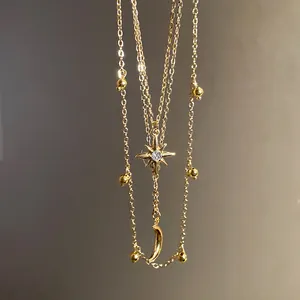 Detailed view of a golden layered necklace featuring star and moon rhinestone pendants