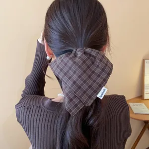 Detail showing a brown plaid fabric oversized scrunchie worn on a ponytail for a minimalist look