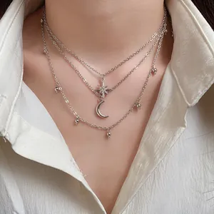 Detail shot of three-layered silver necklace with star and moon charms on a model