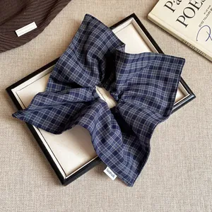 Close-up detail of a blue checkered fabric scrunchie with a visible handmade tag