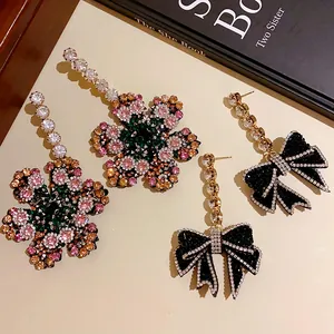 Vue détaillée de boucles d'oreilles fleur en strass et nœud noir avec aiguilles en argent
