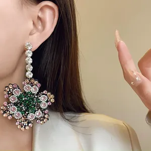 Gros plan sur de grandes boucles d'oreilles fleur en argent avec strass multicolores