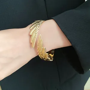 Detail view of a vintage-style gold twisted feather wing open cuff bracelet