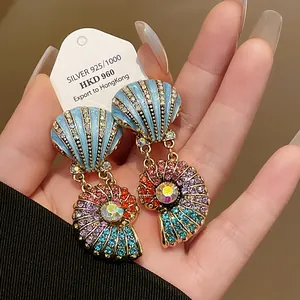 Detailansicht bunter muschelförmiger Ohrringe mit lebendigen Strassverzierungen