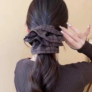 Detailed view of a brown plaid double-layer scrunchie worn on a ponytail hair style