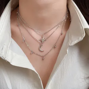 Close-up detail of silver-tone layered star and moon charm necklace on a model