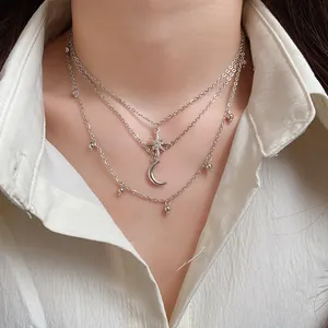 Detailed view of silver-toned layered necklace with star and moon charms on a model