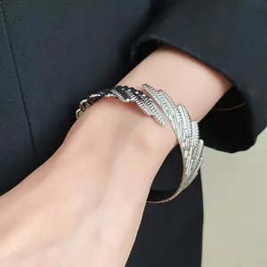 Macro view of a vintage silver-toned feather cuff bracelet worn on a female wrist.