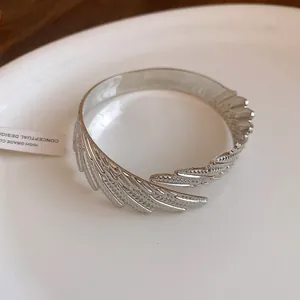 Close-up detail of the intricate silver feather pattern on this twisted metal cuff bracelet