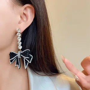 Détail d'élégantes boucles d'oreilles pendantes en strass avec nœud sur le modèle
