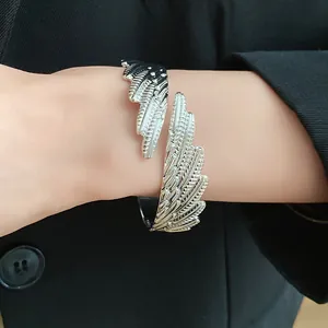 Detailed view of vintage silver metal feather open bangle bracelet worn on a female wrist