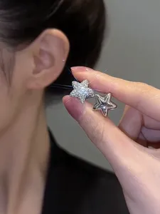 Detailed close-up of sparkling zircon-encrusted and polished silver star earrings