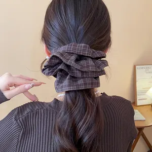 Close-up detail of a brown plaid double-layered fabric scrunchie on a ponytail