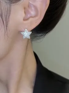 Close-up detail of a silver-toned star earring with sparkling zircon studs on an ear.