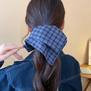 Detailed macro view of a blue plaid fabric scrunchie on long wavy brown hair texture