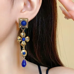 Detailed view of vintage palace style gold drop earrings with blue floral stones