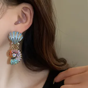 Nahaufnahme von vintage Muschel-Ohrhängern mit bunten Strasssteinen getragen von einem Model