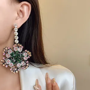 Vue détaillée de boucles d'oreilles pendantes à fleurs en strass portées par un modèle