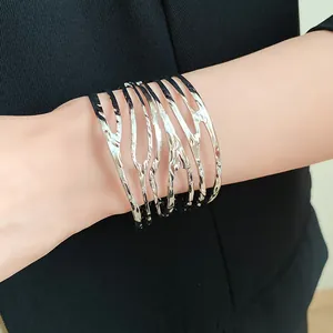 Detailed macro view of a silver-toned metal twisted feather cuff bracelet worn on a wrist.