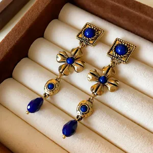 Detailed macro shot of vintage gold earrings with blue gemstones inside a jewelry box