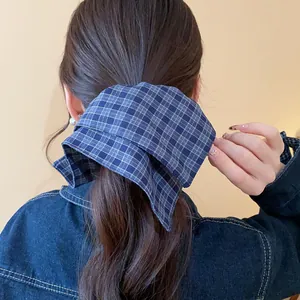 Close-up of a blue plaid fabric layered hair scrunchie styled on a model's ponytail