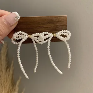 French retro pearl bow stud earrings with elegant dangling tassels in warm white