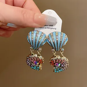 Detailansicht von Vintage-Muschelohrringen mit bunten Strasssteinen und blauem Finish.