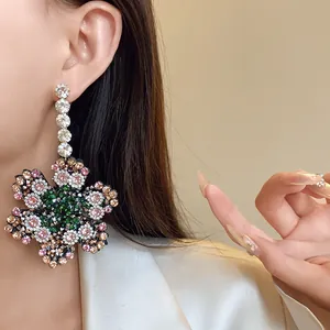 Détail macro de boucles d'oreilles fleur oversize avec cristaux multicolores et argent