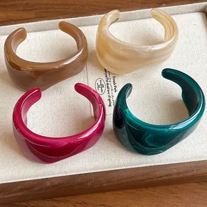 Detail view of four irregular resin open cuff bracelets with vintage marble texture.