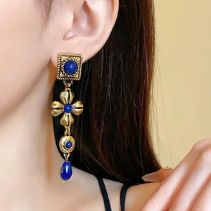Detailed close-up of vintage court style long earrings with blue stones on a model