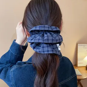 Detailed view of a stylish blue plaid double-layered hair scrunchie worn by a model.