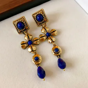Detail view of elegant vintage gold-tone drop earrings with blue stones and flowers